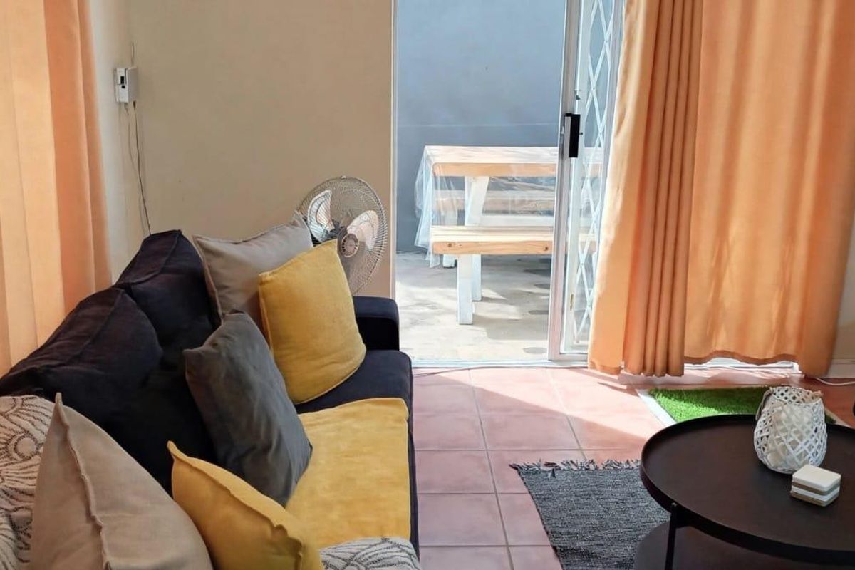 A living room featuring tiled flooring and a sliding glass door providing direct access to an outdoor patio area.