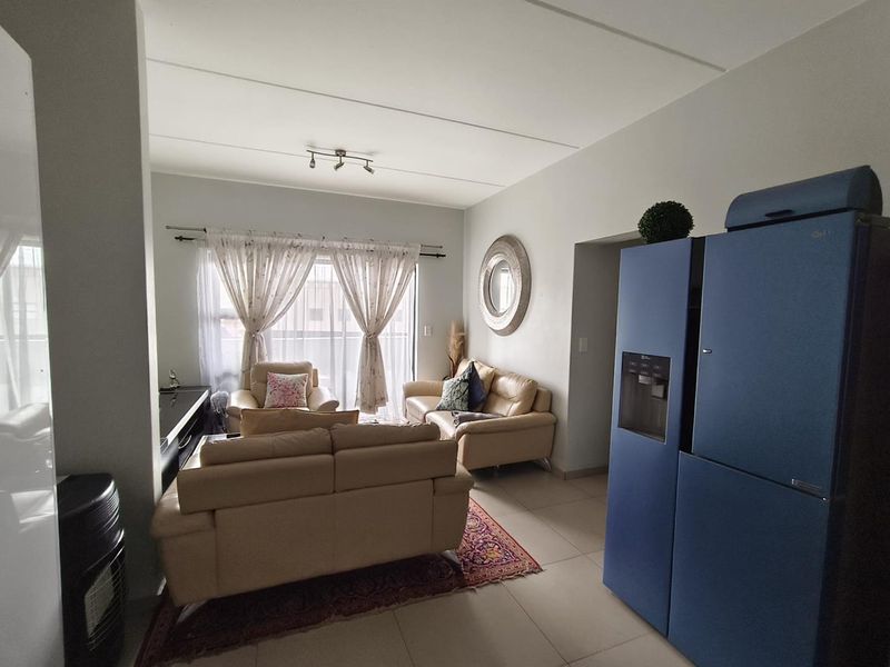 A living room featuring tiled flooring, track lighting, and a sliding glass door providing access to the exterior.