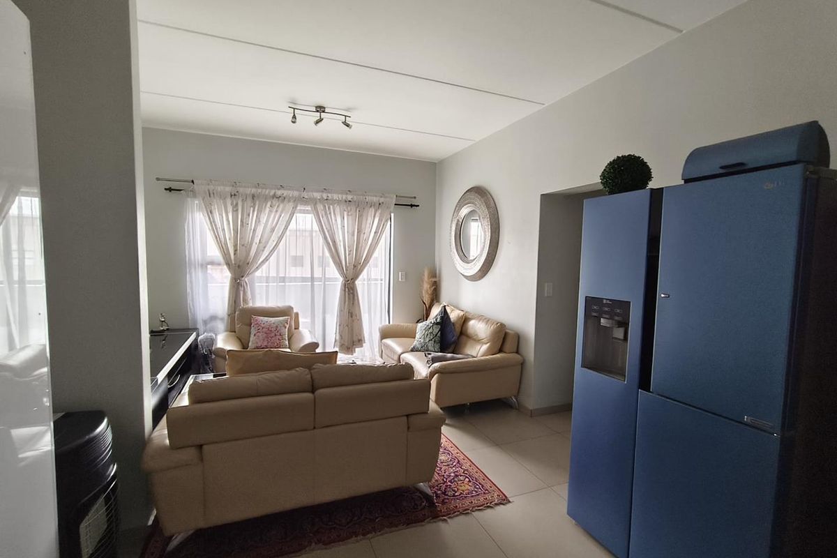 A living room featuring tiled flooring, track lighting, and a sliding glass door providing access to the exterior.