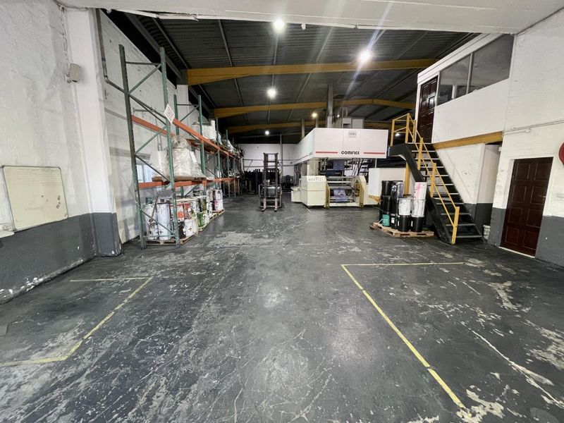 Spacious industrial warehouse area featuring high ceilings with exposed steel trusses, mezzanine access, and durable flooring suitable for manufacturing or storage operations.