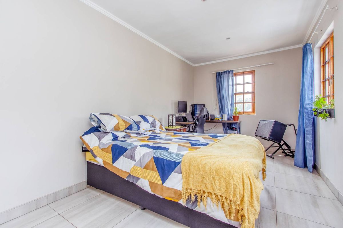 A functional bedroom featuring tiled flooring, timber-framed windows, and neutral wall finishes, offering a versatile space for rest or study.