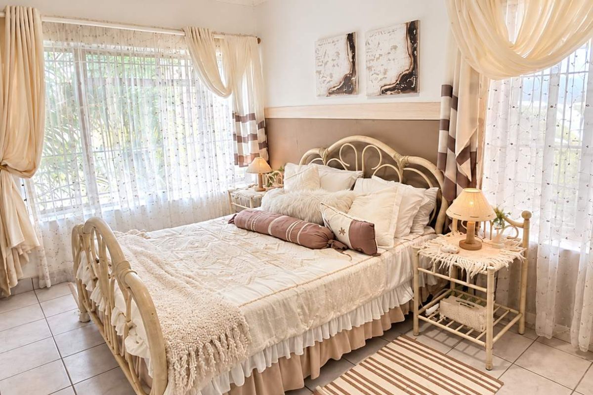 A bright and airy bedroom featuring tiled flooring, large windows allowing ample natural light, and a built-in wardrobe for storage.