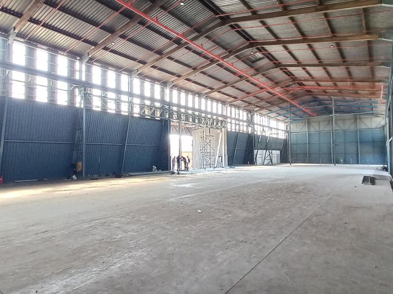 Spacious industrial warehouse featuring a steel portal frame, corrugated metal walls, concrete flooring, and an integrated fire sprinkler system.
