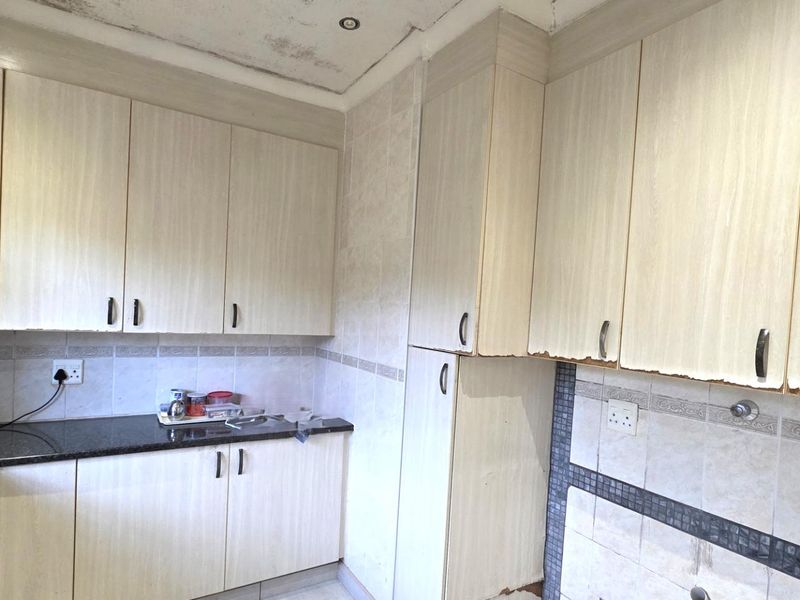 Kitchen featuring built-in cabinetry and granite countertops, currently showing signs of ceiling water damage and wear to the cabinet finishes.