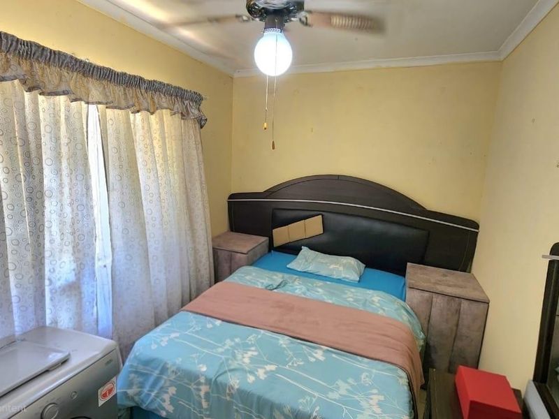 A compact bedroom featuring a ceiling fan and coving, currently requiring cosmetic updates to the wall finishes.