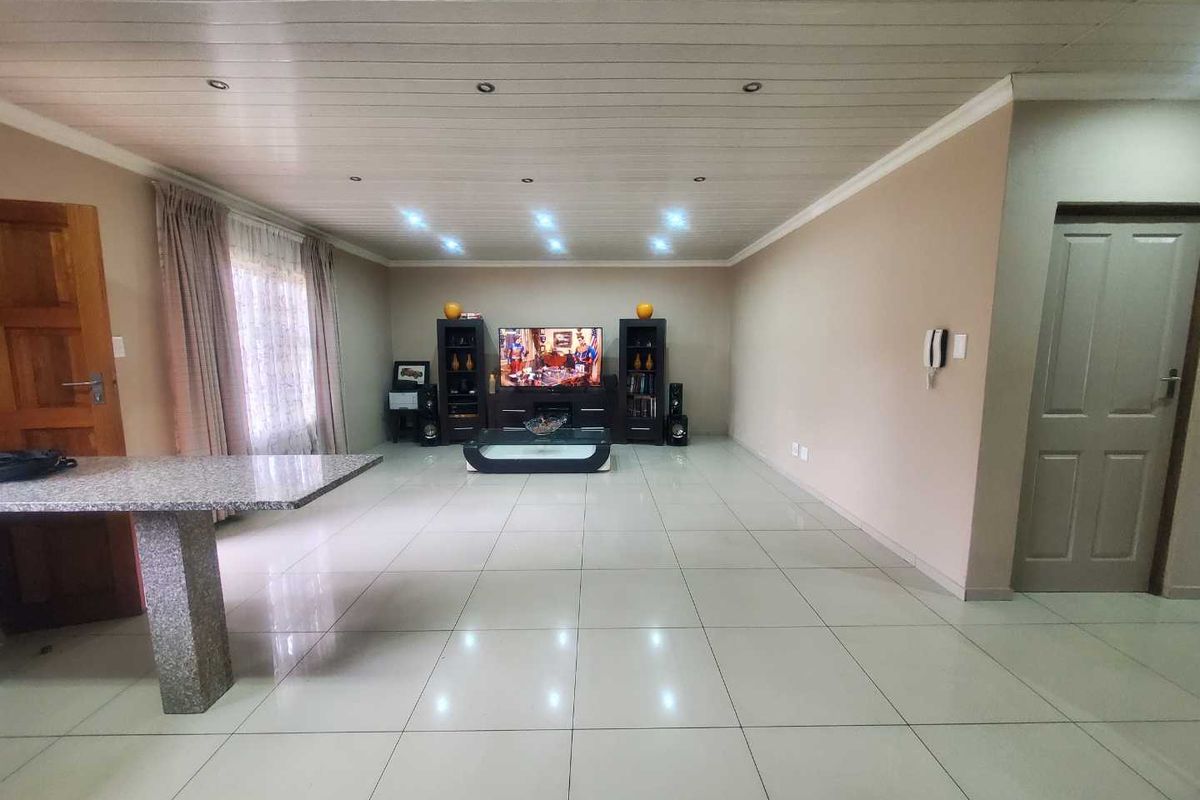 Spacious living area featuring large format floor tiles, recessed downlighting, and a tongue-and-groove style ceiling finish.