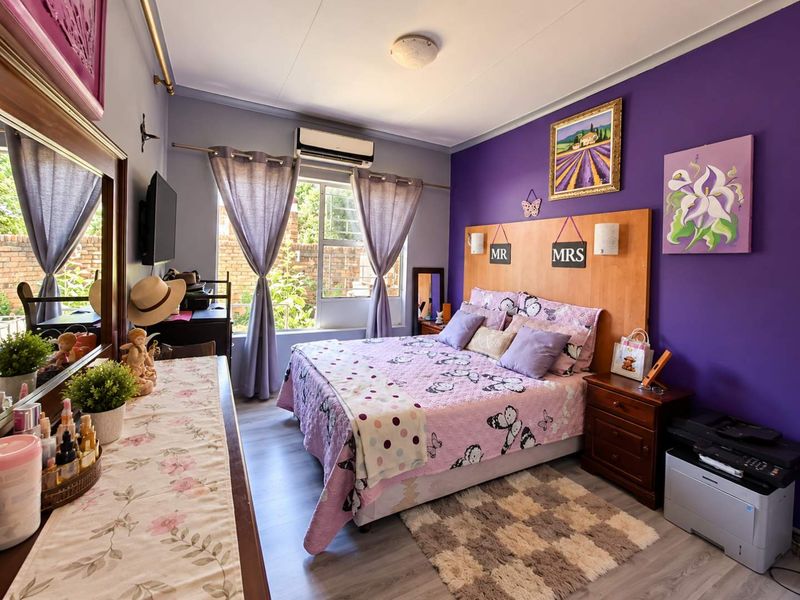 A bedroom featuring laminate flooring, a built-in headboard, and a wall-mounted split-system air conditioner.