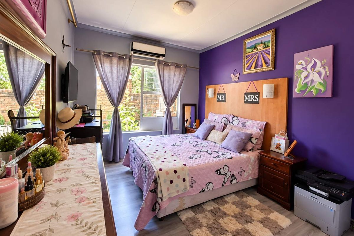 A bedroom featuring laminate flooring, a built-in headboard, and a wall-mounted split-system air conditioner.