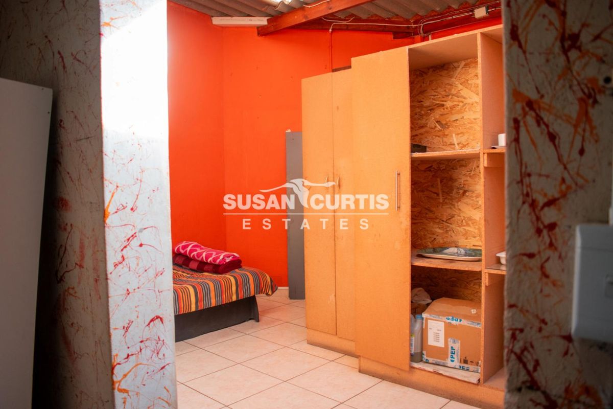 A bedroom featuring tiled flooring, exposed timber rafters, and a built-in wardrobe, requiring cosmetic updates to improve the overall aesthetic.
