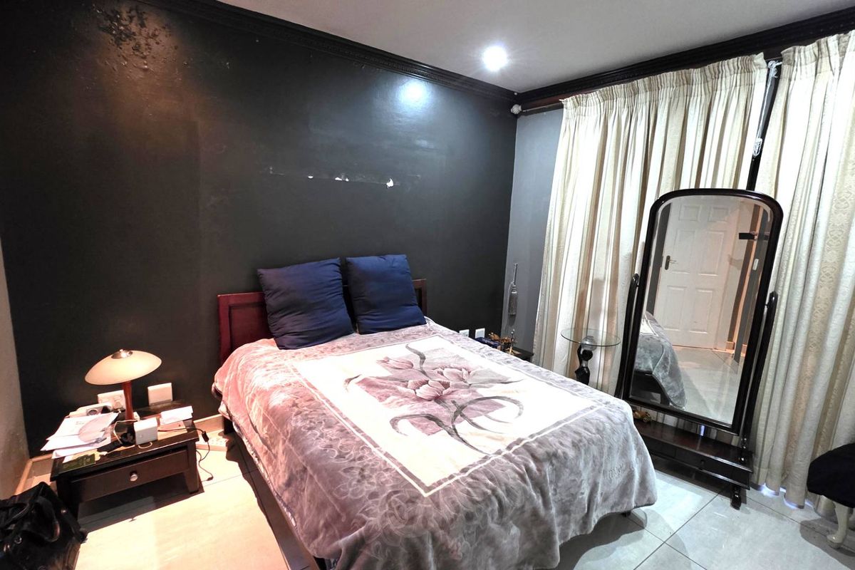A bedroom featuring dark painted walls with crown molding, tiled flooring, and floor-to-ceiling curtains.