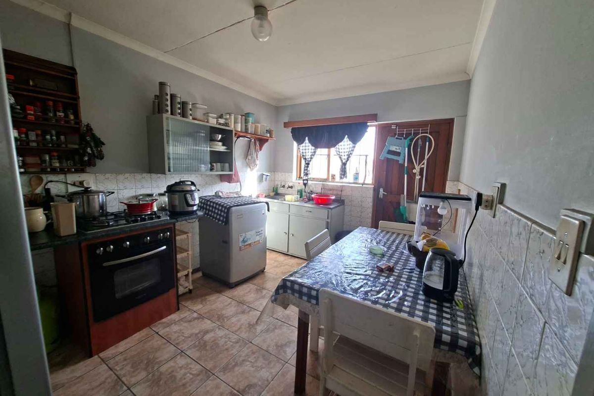 A functional kitchen featuring built-in cabinetry, a gas stove with oven, tiled flooring, and a dedicated dining area.