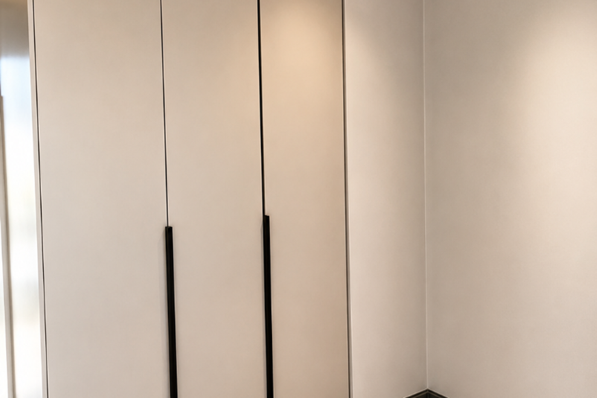 A clean, modern bedroom space featuring neutral-toned built-in wardrobes, recessed ceiling lighting, and contemporary tiled flooring.