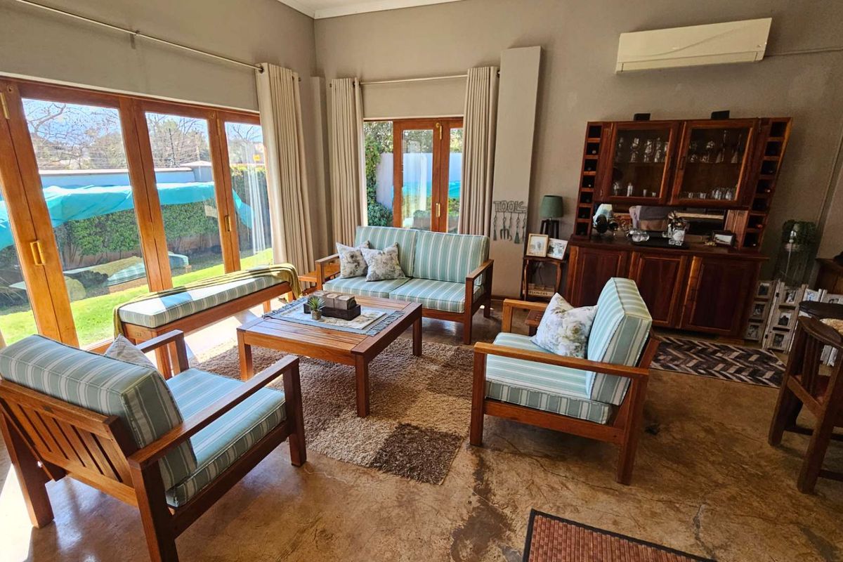 Spacious living room featuring large wooden-framed glass sliding doors, polished concrete floors, and a wall-mounted air conditioning unit.