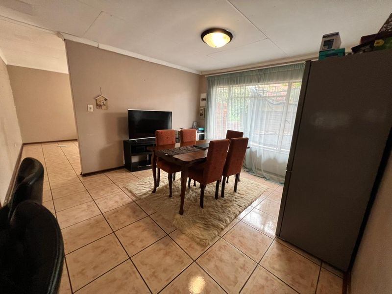 Dining area featuring ceramic tiled flooring and natural light through a large window, offering a functional space for family meals.