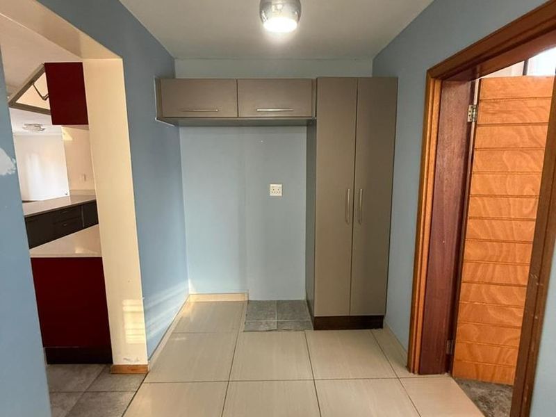 A functional scullery or utility area featuring built-in cabinetry, tiled flooring, and direct access to the adjacent kitchen space.