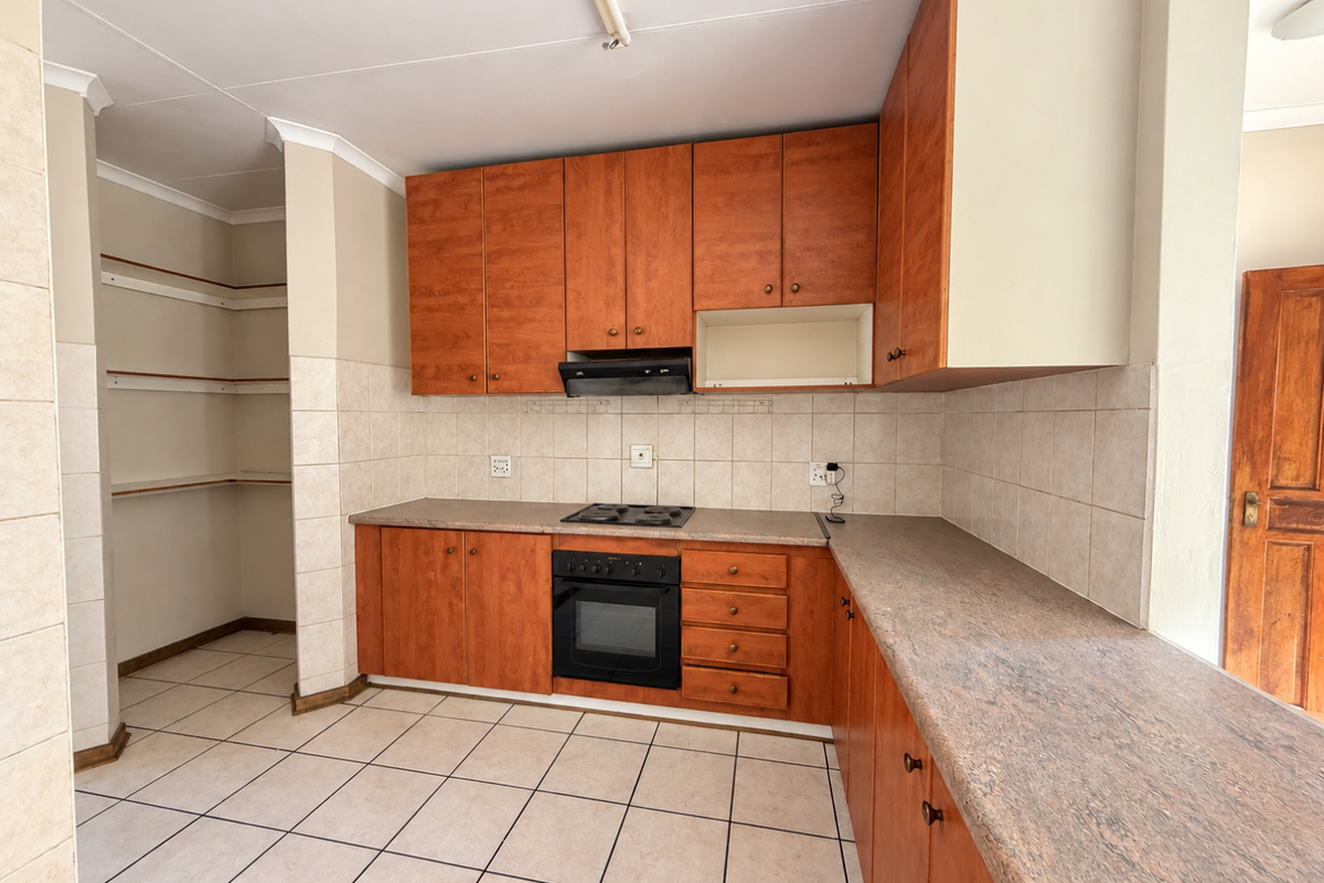 A functional kitchen featuring wood-finish cabinetry, built-in oven and hob, tiled backsplash, and a convenient open-shelving pantry area.