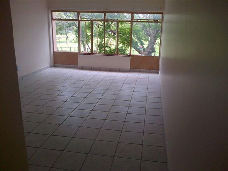 An empty living room featuring tiled flooring and a large window with views, offering a blank canvas for renovation and interior design.