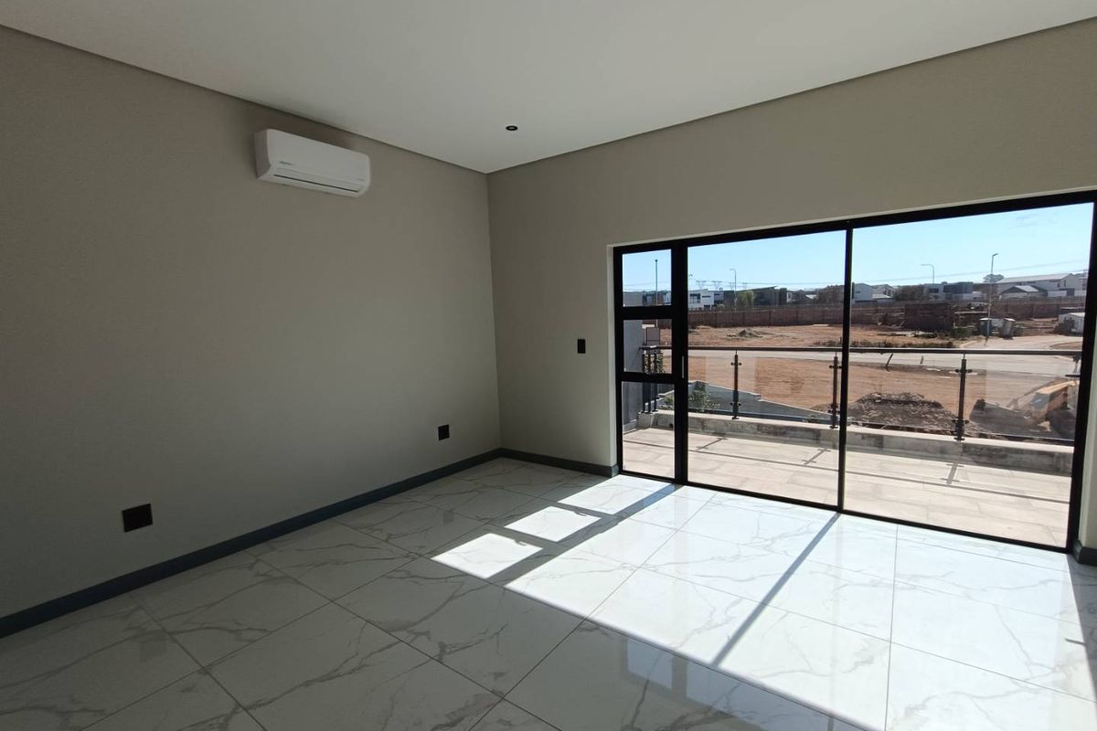Modern, empty bedroom featuring marble-look floor tiles, recessed lighting, a split-system air conditioner, and a sliding glass door leading to a balcony.