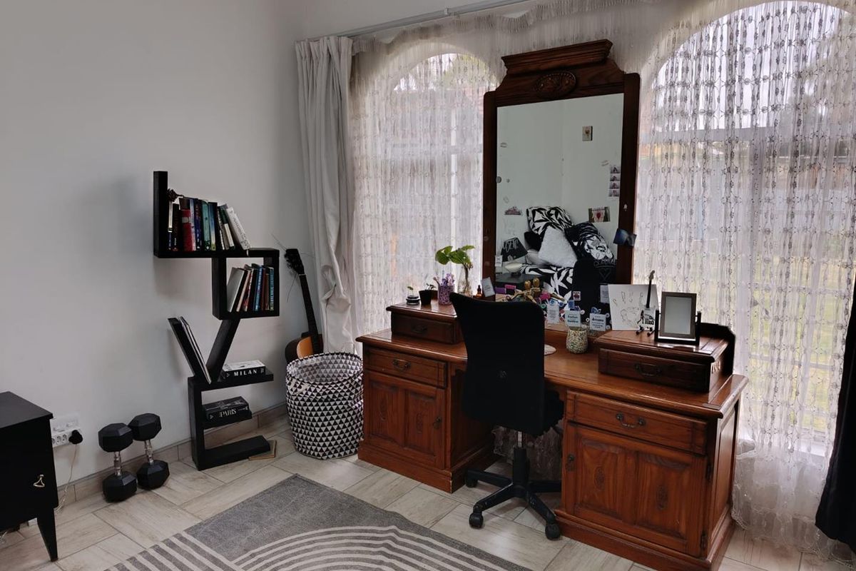 A bedroom featuring tiled flooring and large arched windows that provide natural light.