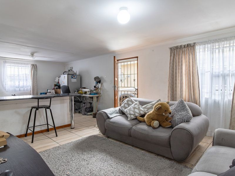 Open plan living area featuring tiled flooring, a breakfast bar, and direct access to an exterior security gate.