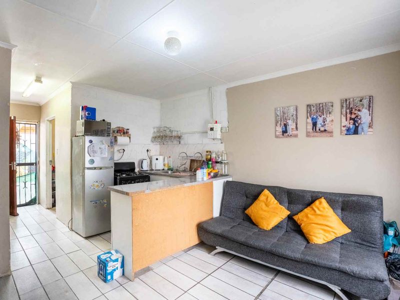 Open-plan living area featuring tiled flooring and a compact kitchen with built-in cabinetry and a gas stove.