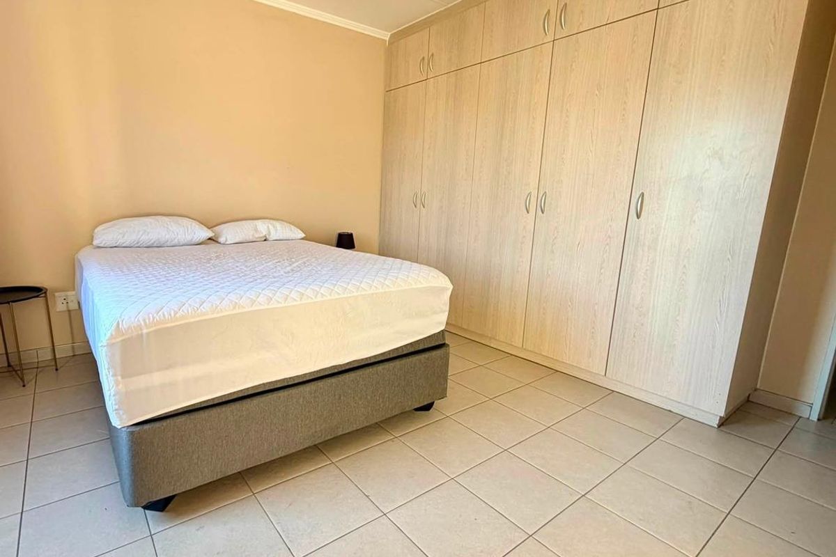 A bedroom featuring light-toned built-in cupboards and neutral tiled flooring, providing a functional and clean living space.