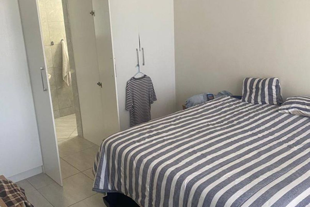 A bedroom featuring tiled flooring and a built-in wardrobe, with an adjoining en-suite bathroom visible through the open door.