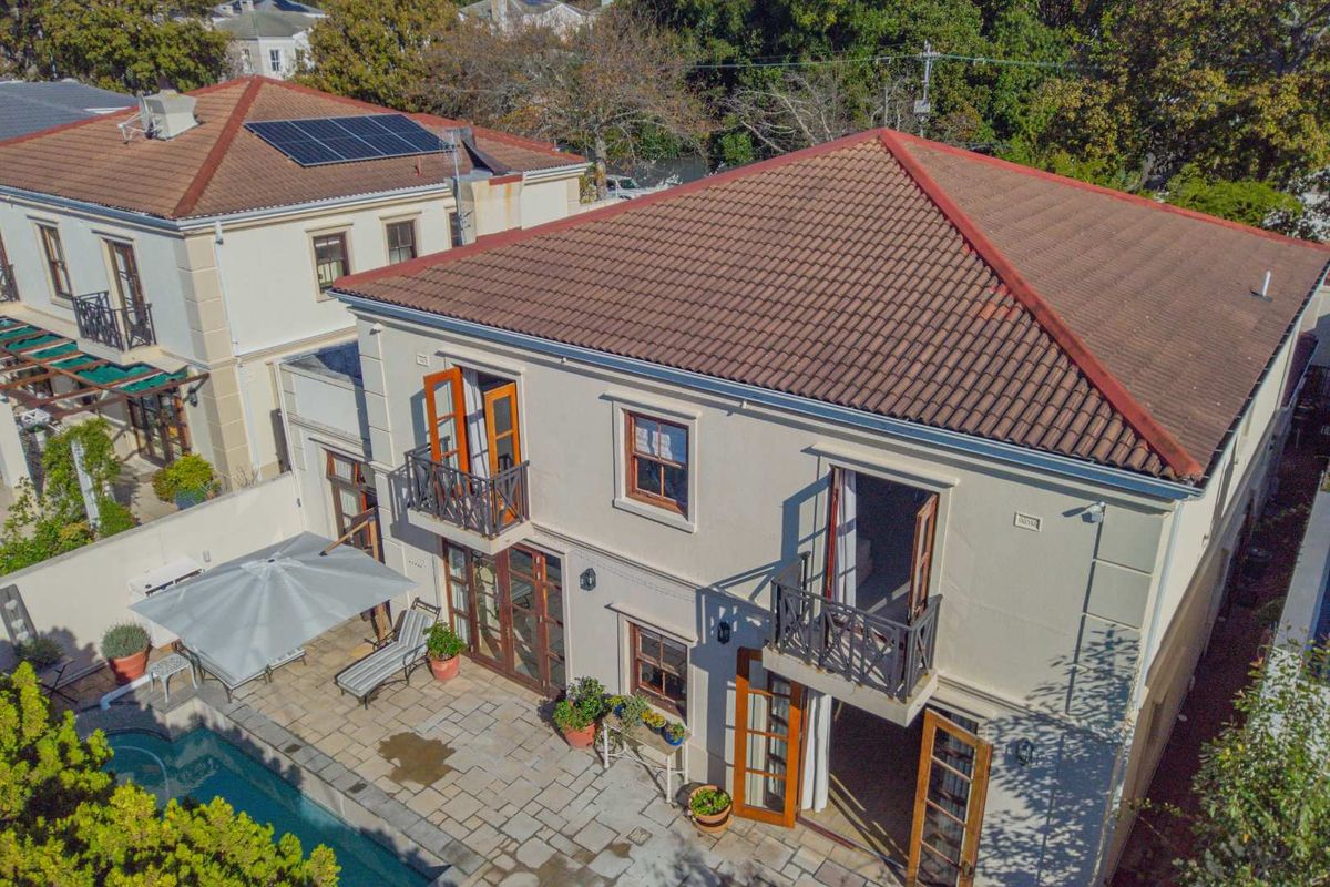 Aerial view of the rear exterior featuring a tiled patio, swimming pool, and double-story facade with balconies and French doors.