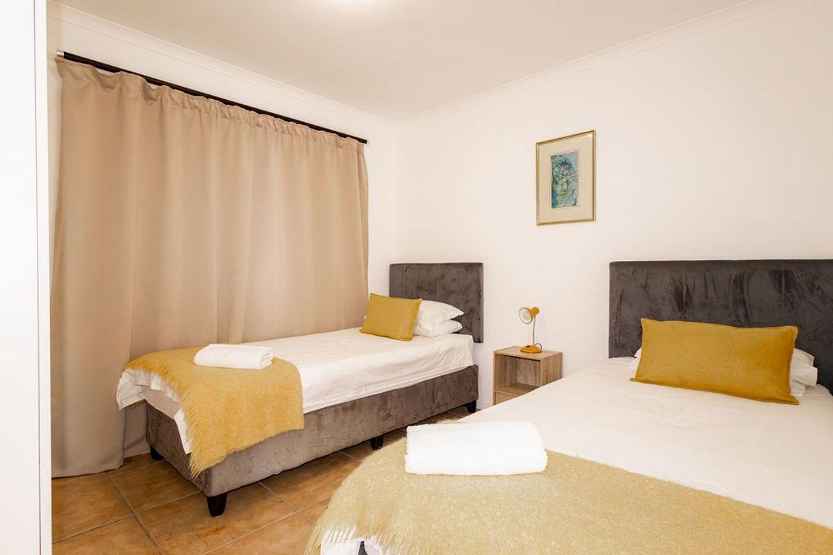 A functional bedroom featuring tiled flooring, neutral wall finishes, and a curtain rail, providing a clean and simple living space.