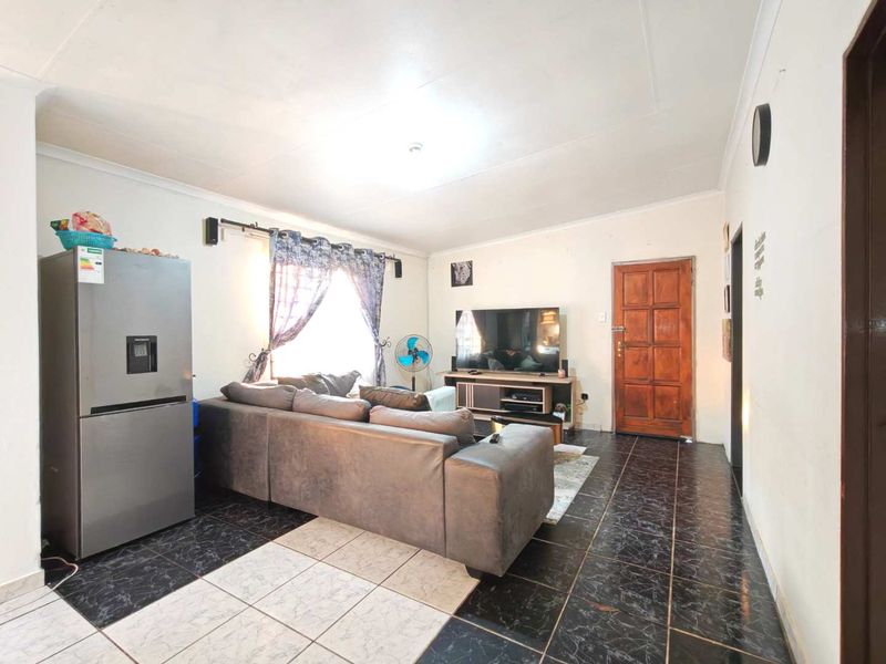 A living room featuring tiled flooring, a timber entrance door, and coved ceilings, providing a functional and open living space.
