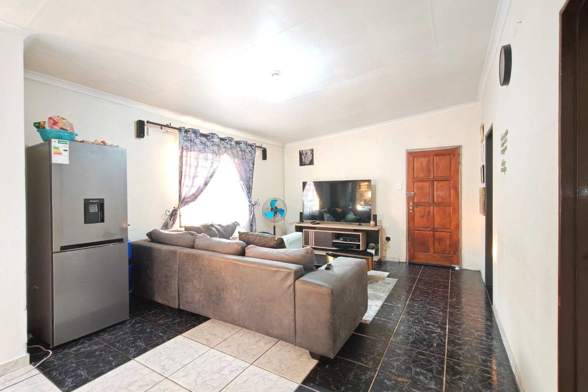 A living room featuring tiled flooring, a timber entrance door, and coved ceilings, providing a functional and open living space.