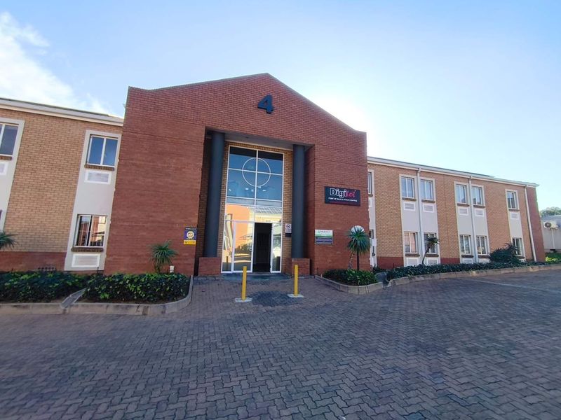 Front exterior view of a professional office building featuring a brick facade, paved driveway, and a prominent glass entrance.