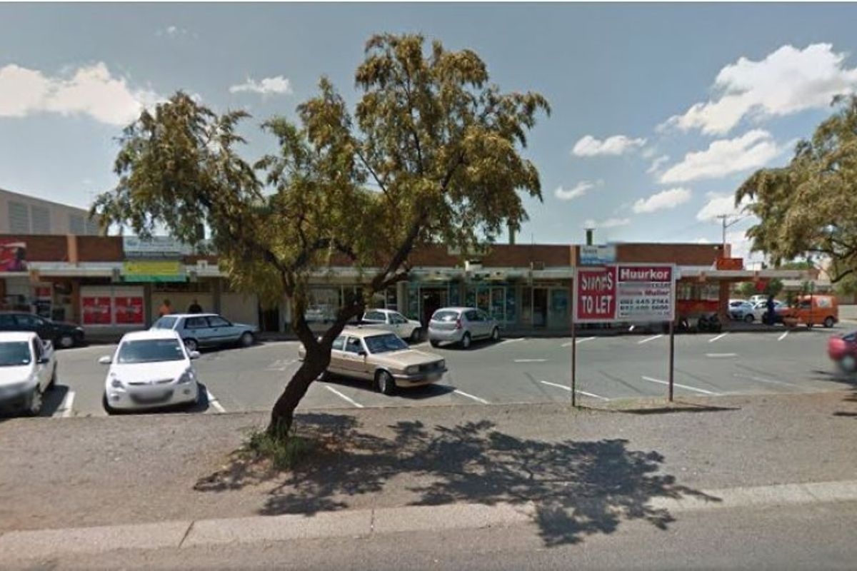 Street view of a commercial property with a paved parking area and storefronts located in Pretoria.