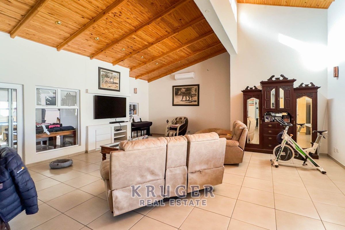 Spacious living room featuring a high vaulted timber-clad ceiling, tiled flooring, and a wall-mounted air conditioning unit.