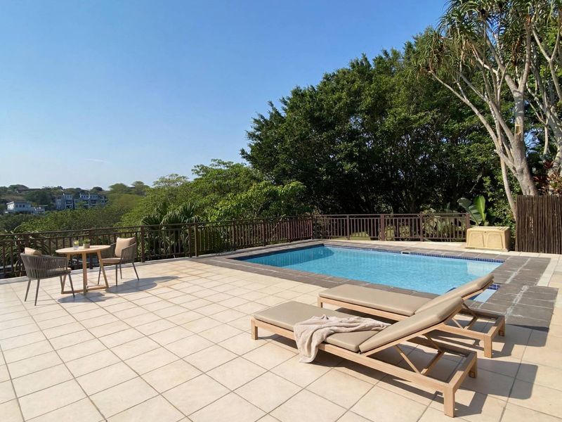 Outdoor pool area featuring a tiled deck, swimming pool, and metal balustrade with scenic views.