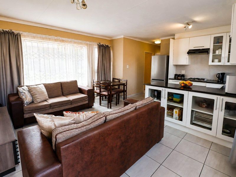 Open-plan living area featuring a modern kitchen with granite countertops, gas hob, and tiled flooring, seamlessly flowing into the dining and lounge space.
