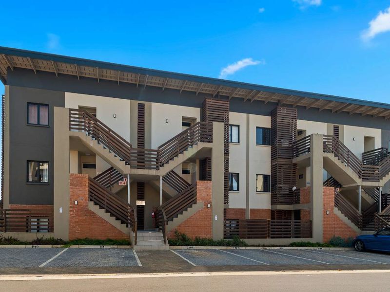 Modern apartment complex exterior featuring brick accents, timber screening, and external staircases with dedicated paved parking bays.