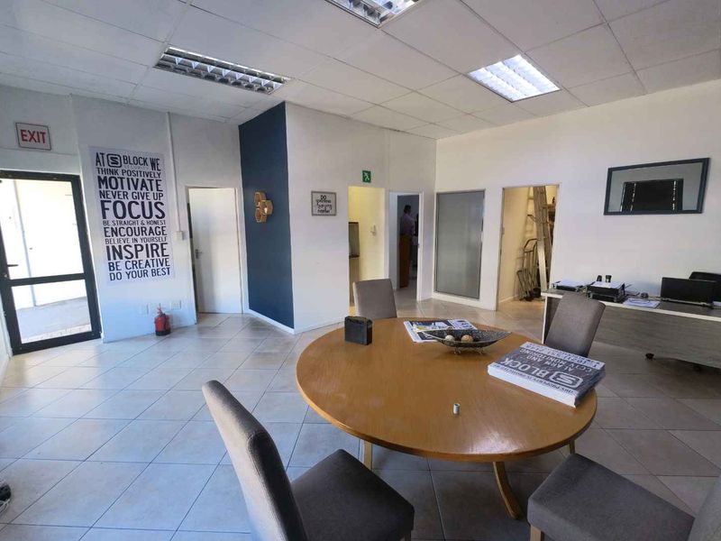 A functional office space featuring tiled flooring, a suspended ceiling with recessed lighting, and multiple internal access points.