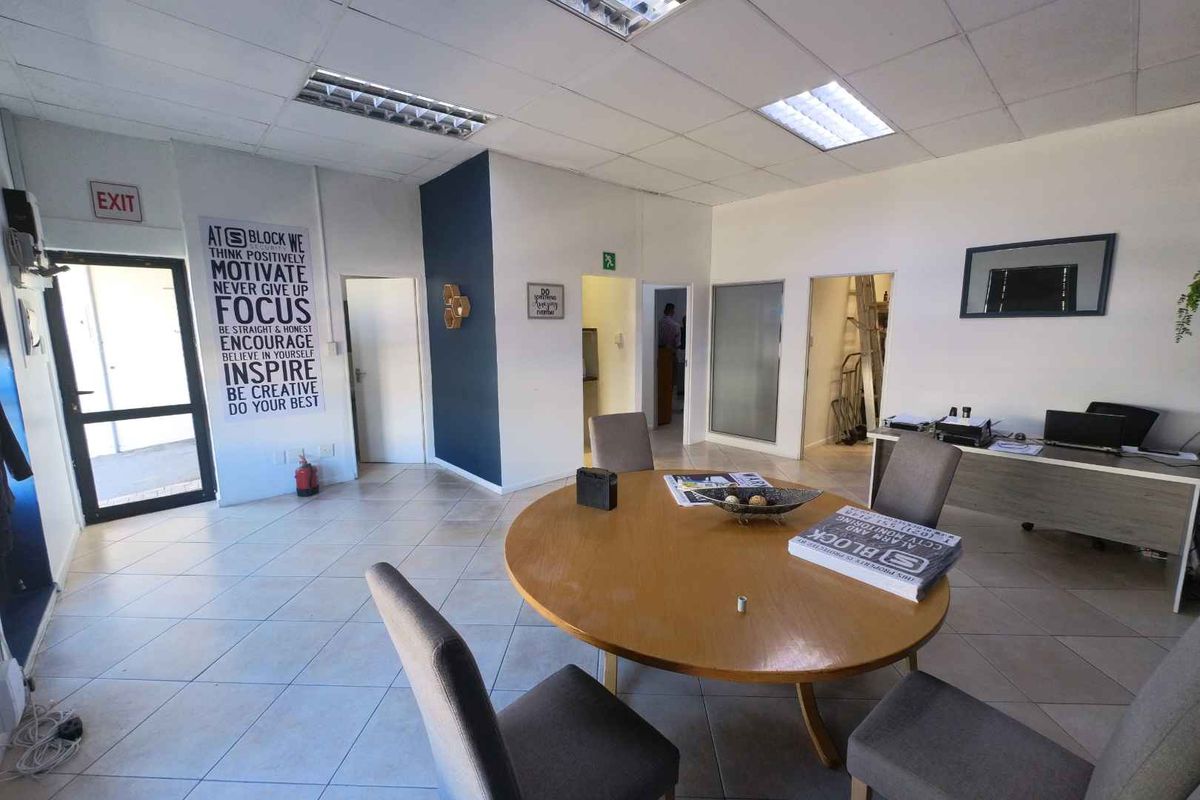 A functional office space featuring tiled flooring, a suspended ceiling with recessed lighting, and multiple internal access points.