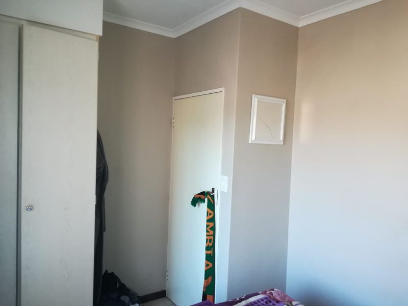 A bedroom interior featuring a built-in wardrobe and neutral wall finishes with decorative cornice detailing.