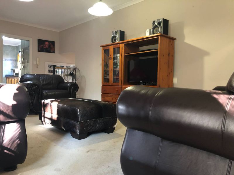 A comfortable living room area featuring neutral wall tones and carpeted flooring, providing a functional space for relaxation and entertainment.