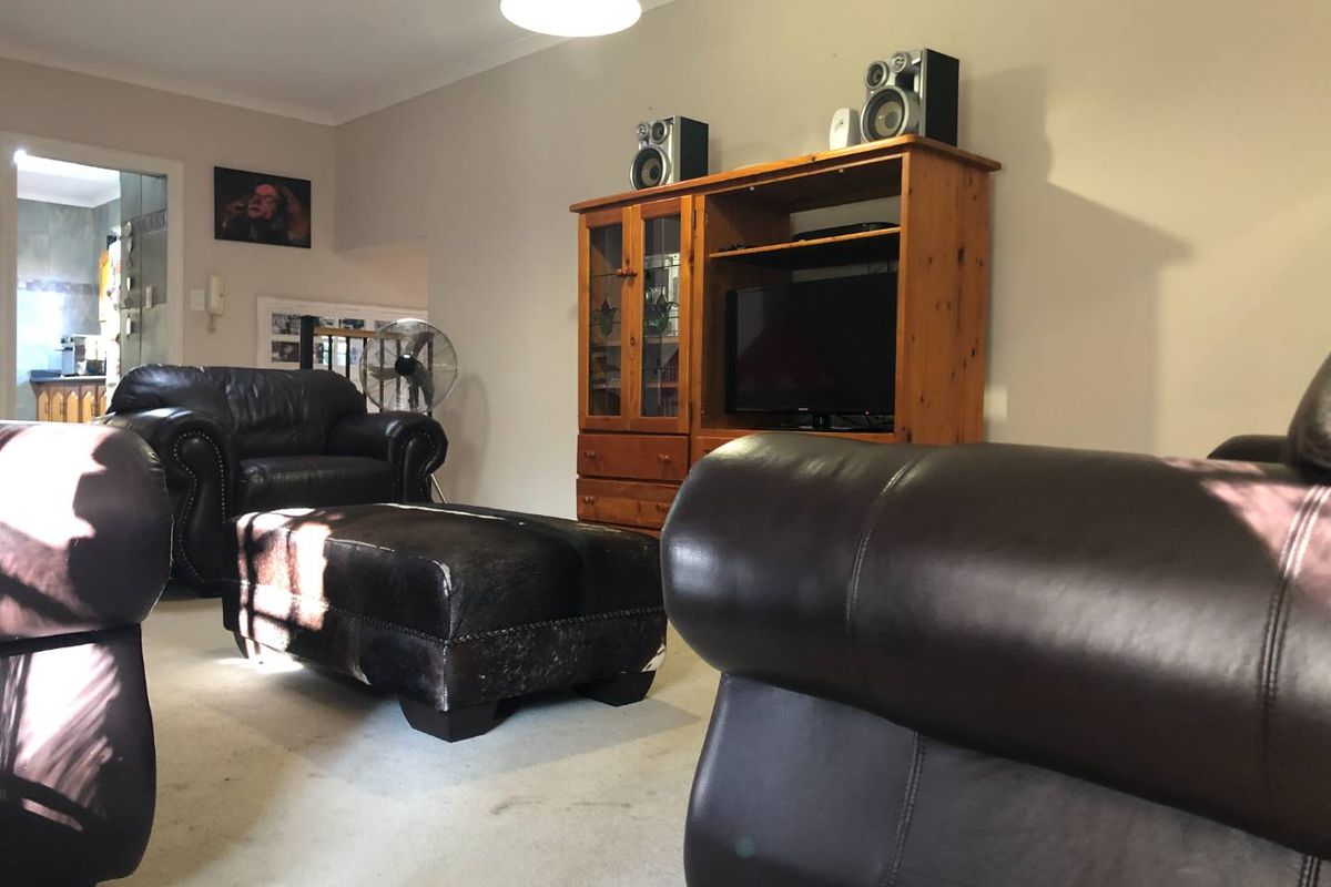 A comfortable living room area featuring neutral wall tones and carpeted flooring, providing a functional space for relaxation and entertainment.