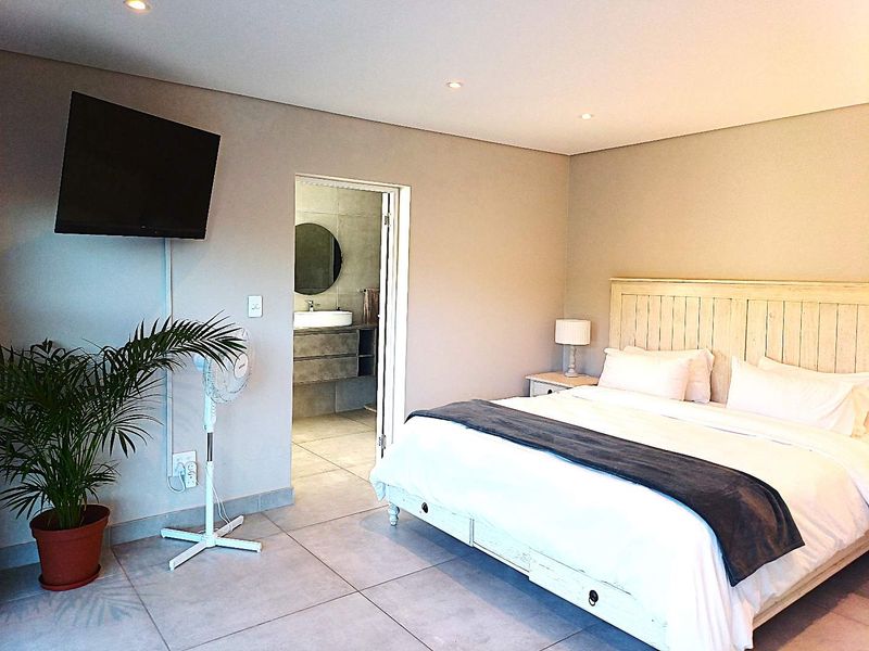 A well-maintained bedroom featuring tiled flooring, recessed lighting, and direct access to an en-suite bathroom.