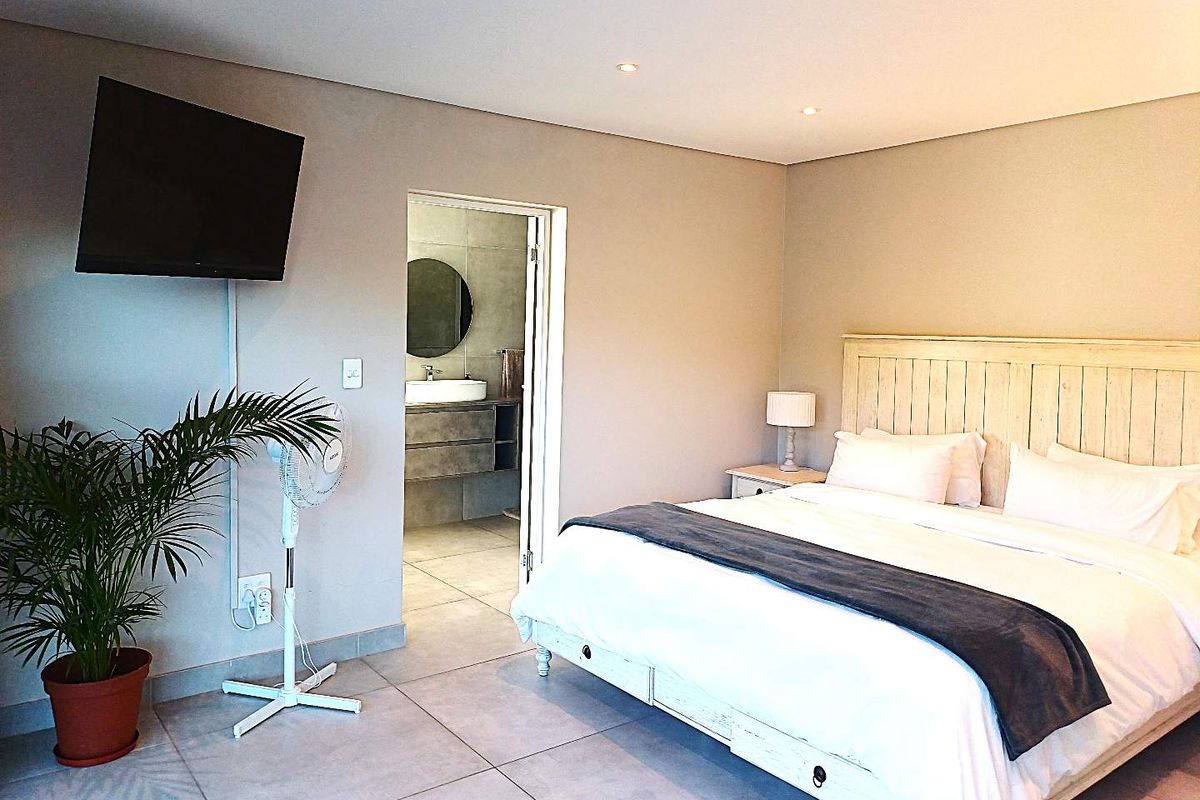 A well-maintained bedroom featuring tiled flooring, recessed lighting, and direct access to an en-suite bathroom.