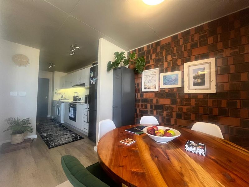 Open-plan living and kitchen area featuring a distinctive brick feature wall, modern cabinetry, and integrated kitchen appliances.