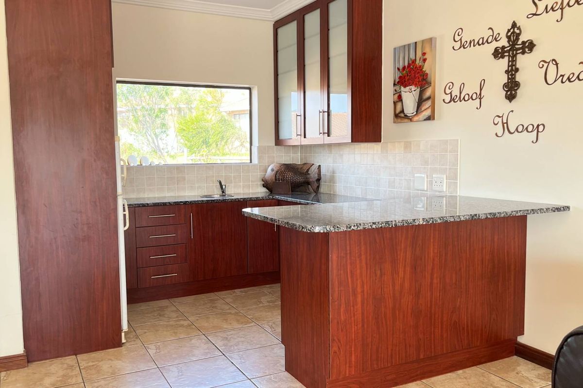 A functional kitchen featuring dark wood cabinetry, granite countertops, tiled backsplash, and a breakfast bar peninsula.