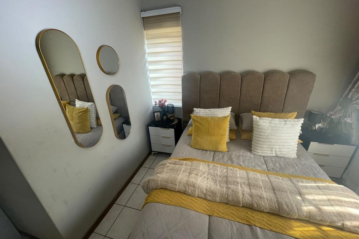 A cozy bedroom featuring tiled flooring and a roller blind, providing a functional and comfortable sleeping space.