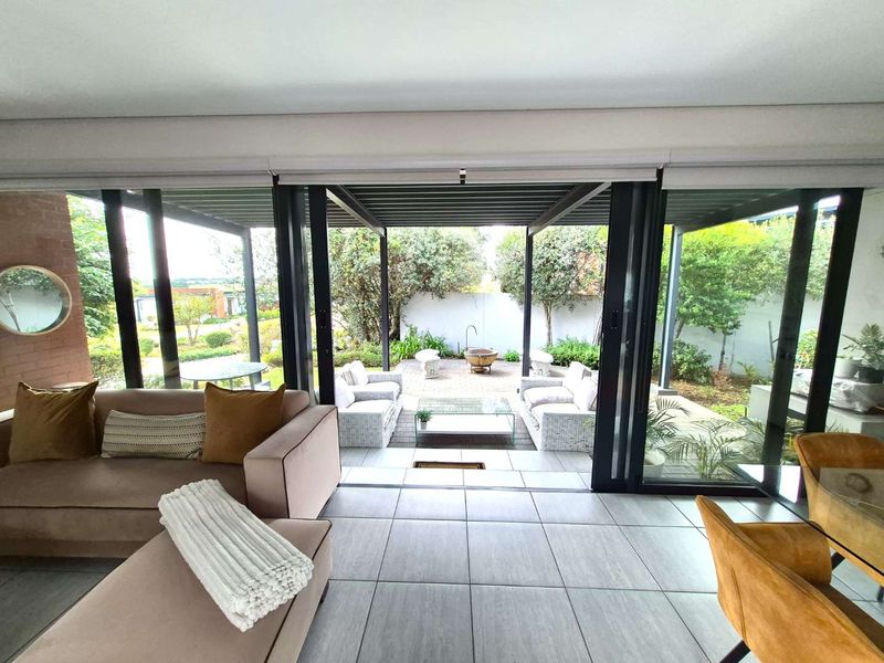 Open-plan living area featuring large sliding glass doors that provide seamless indoor-outdoor flow to a covered patio and garden space.