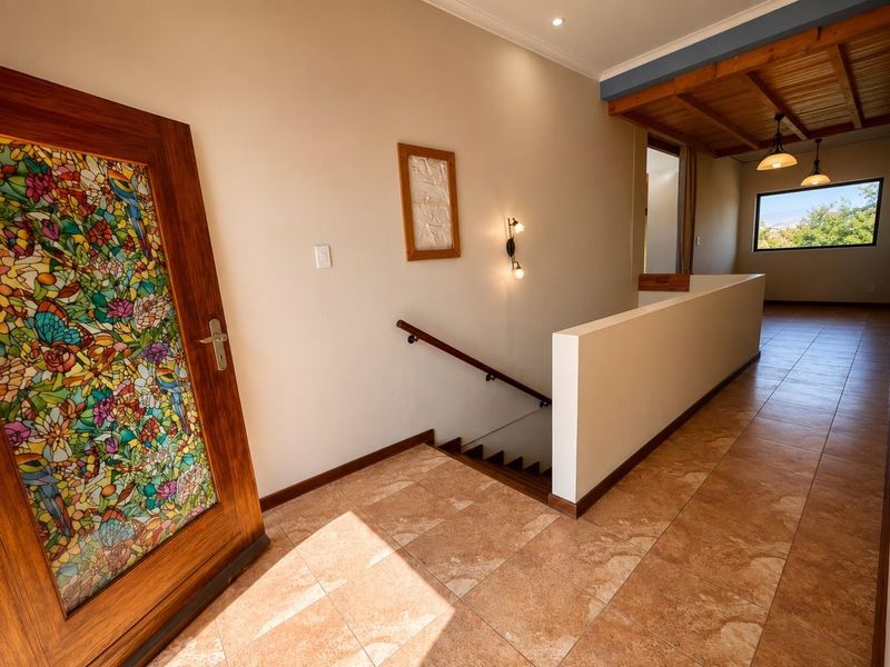 Spacious hallway featuring tiled flooring, a decorative stained glass door, and a staircase with a wooden handrail leading to the lower level.