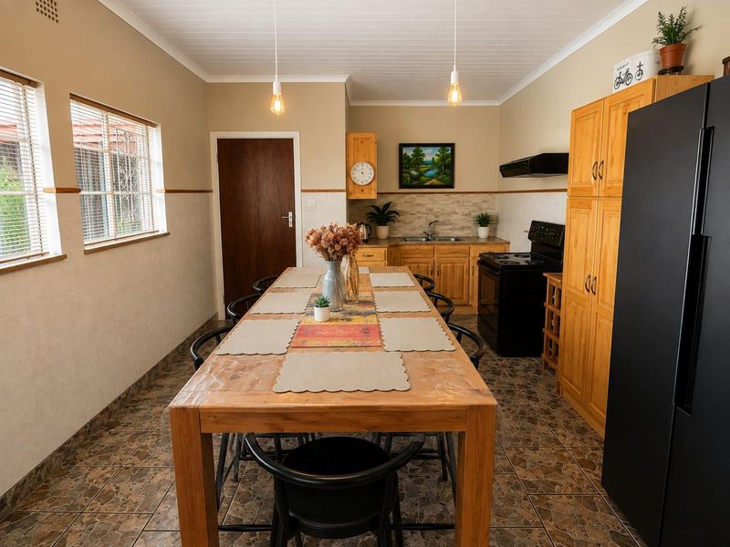 A functional kitchen featuring wooden cabinetry, tiled backsplash, double sink, and built-in pantry storage, with tiled flooring and coved ceiling details.